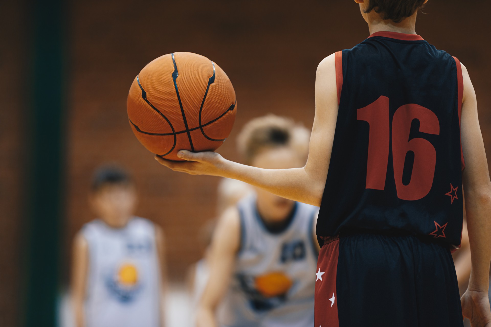 Young basketball player with classic ball. Junior level basketball player holding game ball. Basketball training session for kids